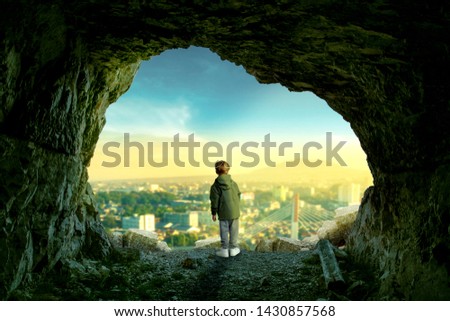 A Manipulation Photography , A Creative Content, child standing at stone caves with city view Royalty-Free Stock Photo #1430857568