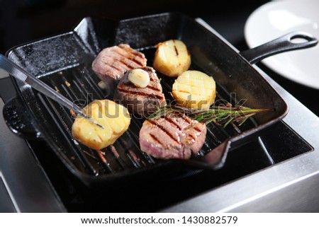 Cooking a piece of beef on the grill indoors. Cooks hands in the frame. Fillet of beef minion. The cook turns the pieces of meat with tweezers.