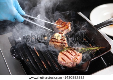 Cooking a piece of beef on the grill indoors. Cooks hands in the frame. Fillet of beef minion. Thin part of the tenderloin. Delicious dish of natural meat.