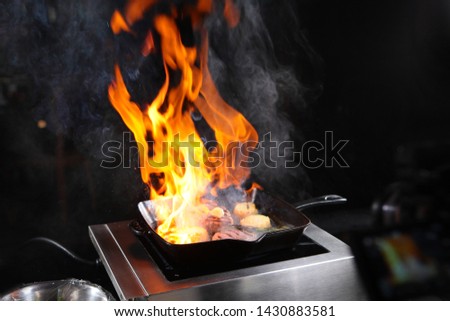 The process of cooking alcohol on a grill pan while cooking filet mignon with vegetables. The concept of cooking a grilled dish indoors.