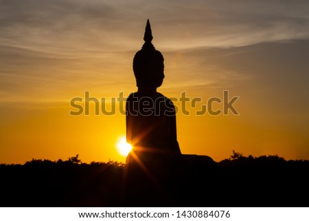 Silhouette at sunset of Big golden buddha, back light.