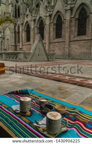 Drinking coffee outside Quito's cathedral entrance. Gothic architecture with stone facade and arch doorways. Peruvian table cloth at local coffee shop. Symmetry. Shot in Ecuador.