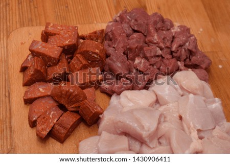 Fresh diced meat and vegetables on a wooden board preparing for skewers