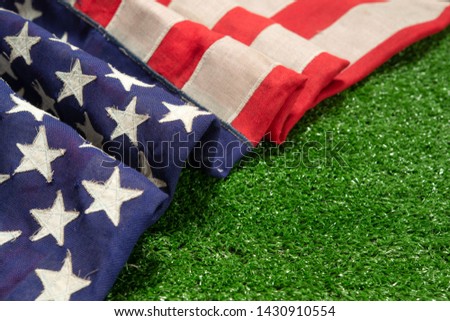 Red, white, and blue old American flag on grass for Memorial Day or Veteran's day background