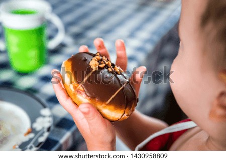 chocolate donut in child hands over table