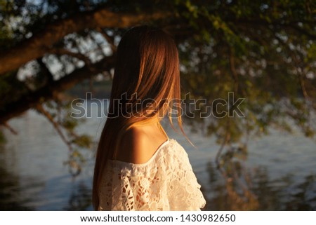 A girl in a white dress. In the water at sunset.