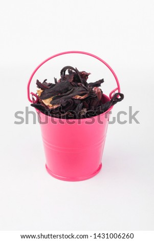 Heap dry hibiscus petals in pink bucket on white background. Copy space