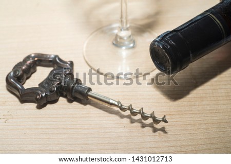 vintage wine opener, glass and wine bottle on a wooden background
