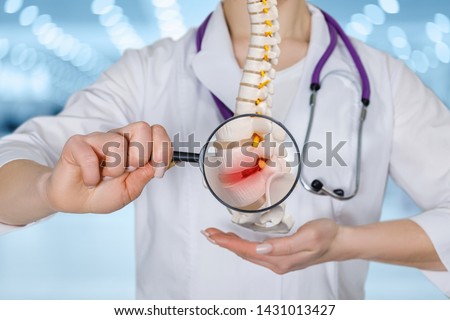 Doctor with a magnifying glass shows intervertebral hernia.