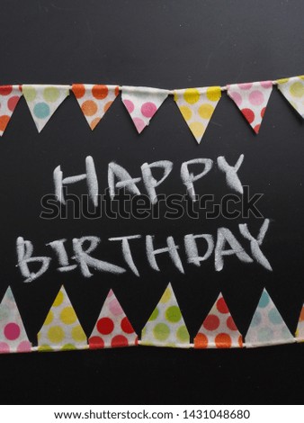 Colorful birthday party flag garland with "HAPPY BIRTHDAY" message on blackboard