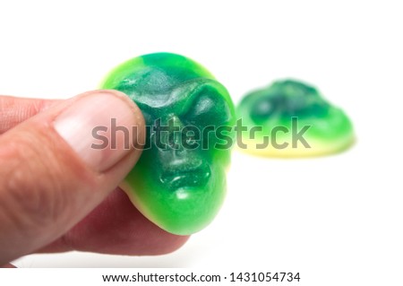 Closeup of candies in shaped alien face in hand on white background 