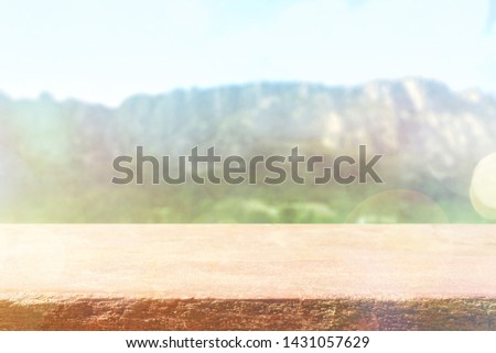 Table top with blurred mountains, sky and cloud in sunny day for product display job showing. Wooden table on green background for display or montage your products.
