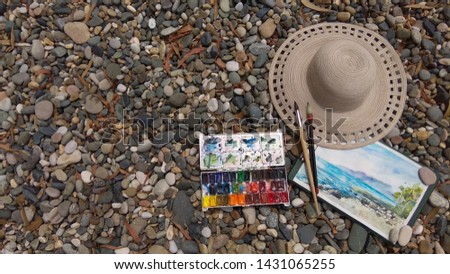 Sketchbook in travels. Sketch of the sea. Painting, paint, brush, hat on the beach.