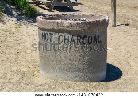 cement beach grill labeled hot charcoal on beach sand
