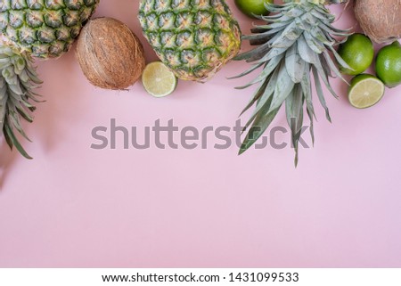 Summer composition. Tropical fruits - pineapple, coconut, lime on pastel pink background. Summer concept. Flat lay, top view, copy space