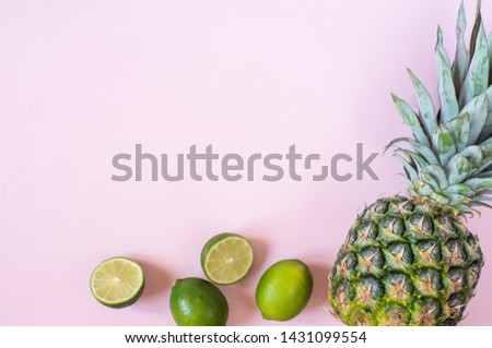 Summer composition. Tropical fruits - pineapple, lime on pastel pink background. Summer concept. Flat lay, top view, copy space