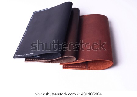 Three handmade leather passport covers isolated on white background. Covers are closed. Closeup view. Covers are dark blue, red and brown.