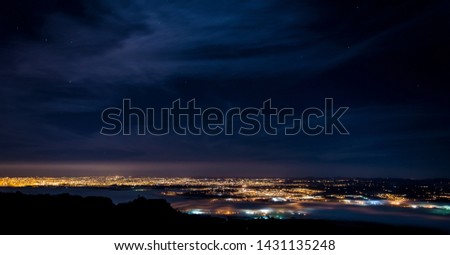
Photograph from above the mountain at night, city lights.