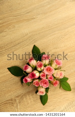 Delicate bouquet of pink roses on a light wooden background. Free space for text at the top. Background, close-up, vertical. Holiday concept.