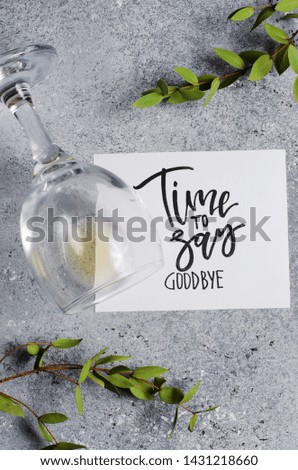 Time to say goodbye. The inscription on a white paper sheet. White wine in a glass glass. Concept - deterioration of relations between people.