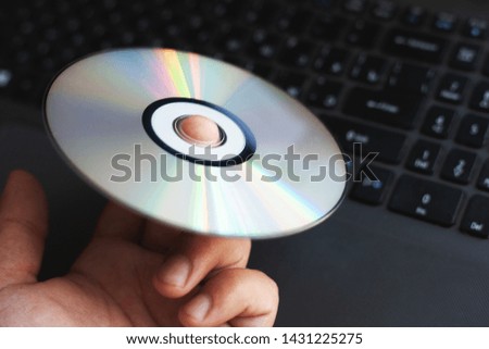 The driver CD compact disc is on the index finger against the background of a computer close-up