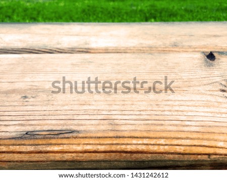 The edge of a wooden table on a background of green grass. Close-up.