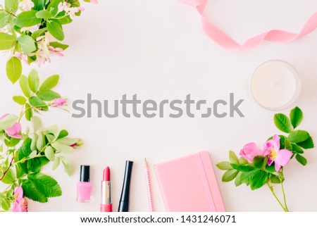 Flat lay blogger or freelancer workspace with a notebook, pink flower on a white background