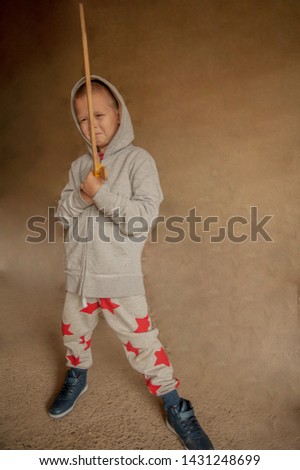 Funny child in old military clothers with wooden sword. Boy dreams of battles, victories and adventures. Concept training of spirit, education morale, patriotizm 