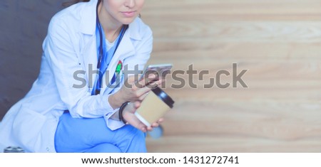 Young woman doctor sitting with your phone. Woman doctors.