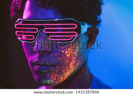 Handsome boy dancing at the rave party with fluorescent paintings on his face Royalty-Free Stock Photo #1431287846