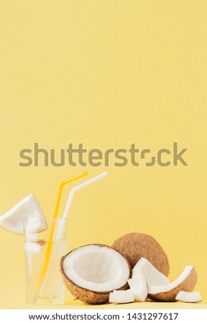 Fresh Coconut cocktail with a straws on yellow background, copy space.