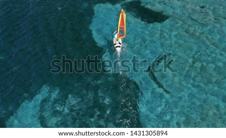 Aerial photo of fit woman practising wind surfing in tropical exotic turquoise bay with natural clear sea