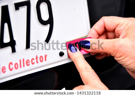 Female fingers and hands applying license plate registration annual sticker