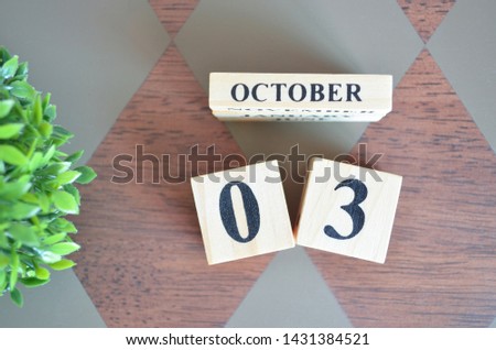 Date of October with leaf on diamond pattern table for background.