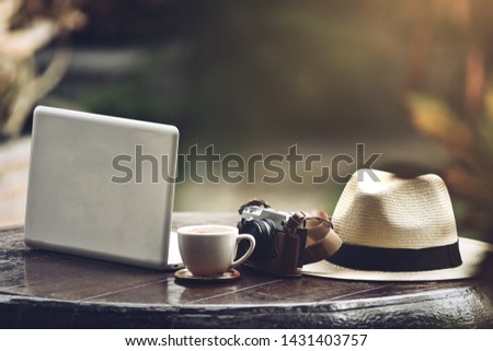 Businesses happen everywhere, just have inspiration. The picture of white laptop, a cup of coffee, vintage camera and white panama hat on wooden table on blurred background. selective focus	
