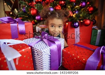 Happy little child with gifts and Christmas tree and lights
