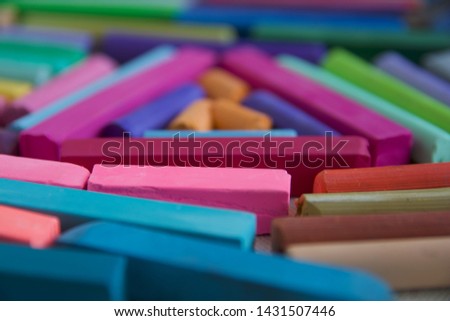 Blurred photo with chopsticks of multicolored art pastels suitable for the background. Symbol of creativity, joy, rich choice.
