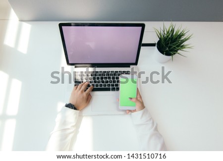 Corporate Laptop mockup on desk with smartphone and plant at workspace