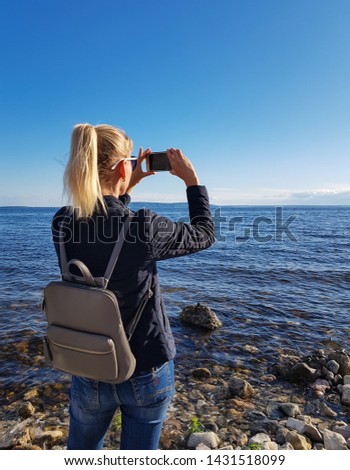A tourist girl or a traveler with a backpack makes a photo or talks on an online chat or tells subscribers about something.