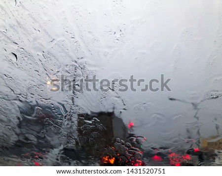 Rainy day concept. Blurred traffic jam and rain drop on glass window as background