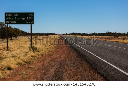 A roadside highway sign with distances to Earldunda, Alice Springs and then days of driving away to Darwin all along the same piece of road showing how large Australia is.