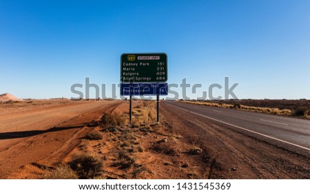 A roadside highway sign with distances to Cadney Park, Marla, Kulgera and Alice Springs and then the next major rest area along the Stuart Highway in Pootnoura.
