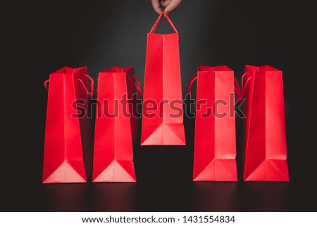 Hand choosing Red Paper Shopping Bag With Black background, selective focus, Planning to Shopping. Choose what's the best concepts.