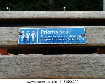 Sign on wooden bench says "Priority Seat for people who are disable, pregnant or less able to stand" 