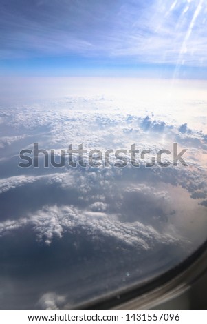 Airplane window overlooking the beautiful clouds and the earth. Sunset in flight on vacation. Tourist theme. Stock photo