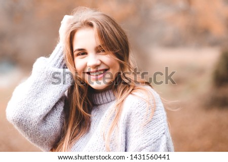 Smiling teen 14-16 year old wearing warm sweater outdoors. Looking at camera. Autumn season. 20s.  Royalty-Free Stock Photo #1431560441