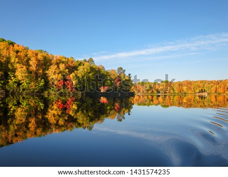 Fall colors trees reflection blue lake waters. Horizontal autumn landscape. No people.