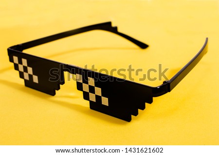 Close up view of meme pixel glasses isolated on a yellow background.