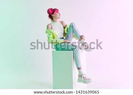 woman with pink hair sits on a cube in stylish clothes