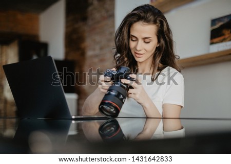 Young freelance female photographer at home, working on laptop in home office